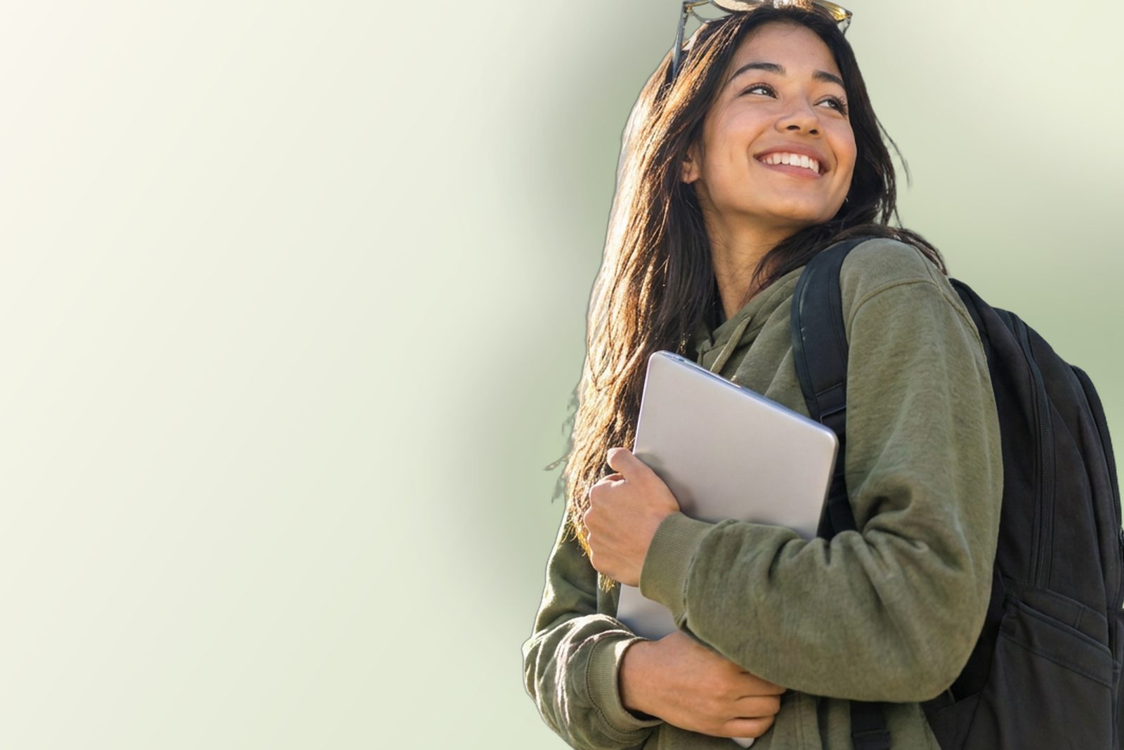 Smiling young woman with a backpack holding a laptop
